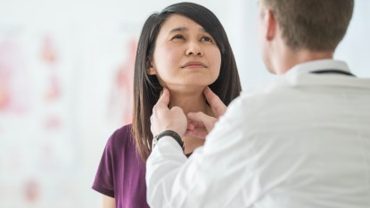 Doctor checking woman's thyroid glands
