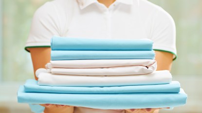 woman holding pile of folded fitted sheets