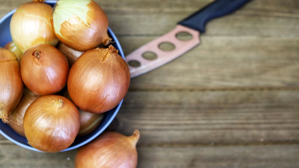 Bowl of onions with knife behind them