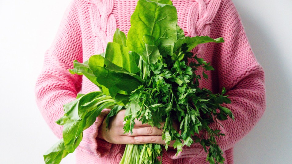 Woman in pink sweater holding leafy greens