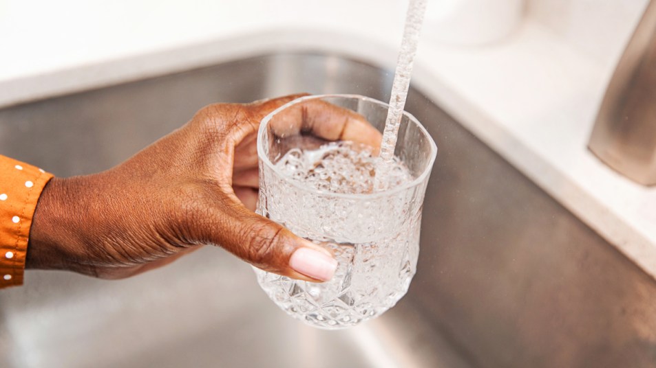 Woman's hand filling glass with tap water