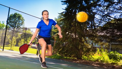 Woman in blue shirt playing pickleball