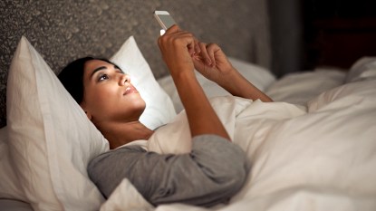 Woman in bed staring at her phone
