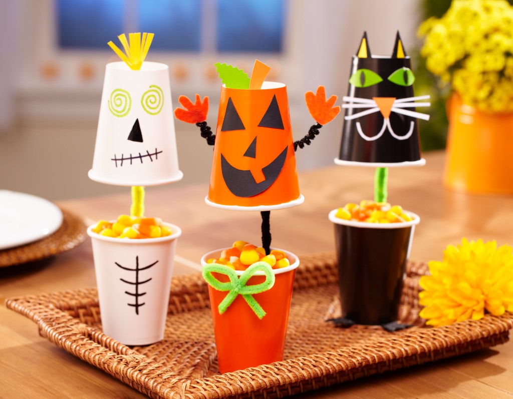 Halloween Centerpiece Ideas: Treat Cups that are decorated like cute characters including a skeleton, a pumpkin and a cat. Cups are filled with candy and served on a tray