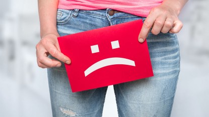 woman holding a sad face sign over her bladder