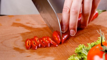 Woman's hands slicing red hot pepper