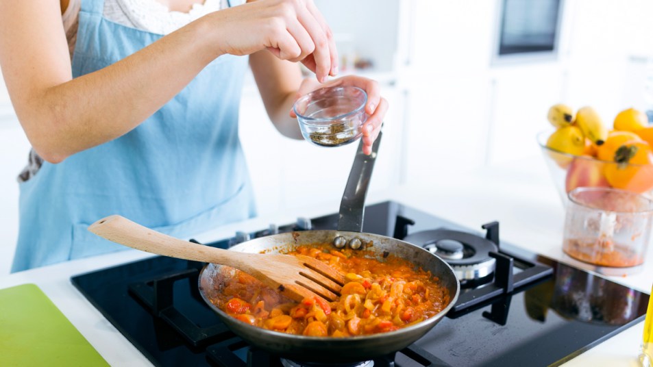 Woman adding spice to pan