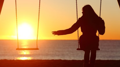 A woman sitting on a swing looking to her side and seeing no one there