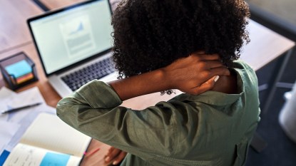 Woman at computer holding back of her neck