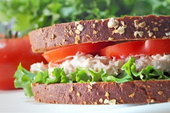 Tuna fish sandwich on whole grain wheat bread with lettuce and tomato.
