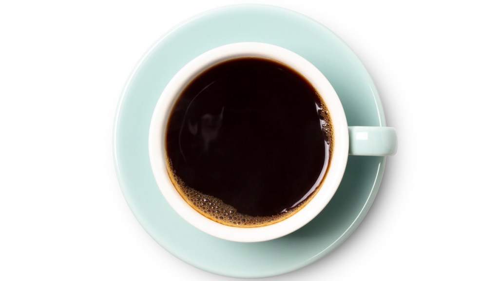 A cup of black roast coffee, which has chlorogenic acid, on a teal saucer and white background