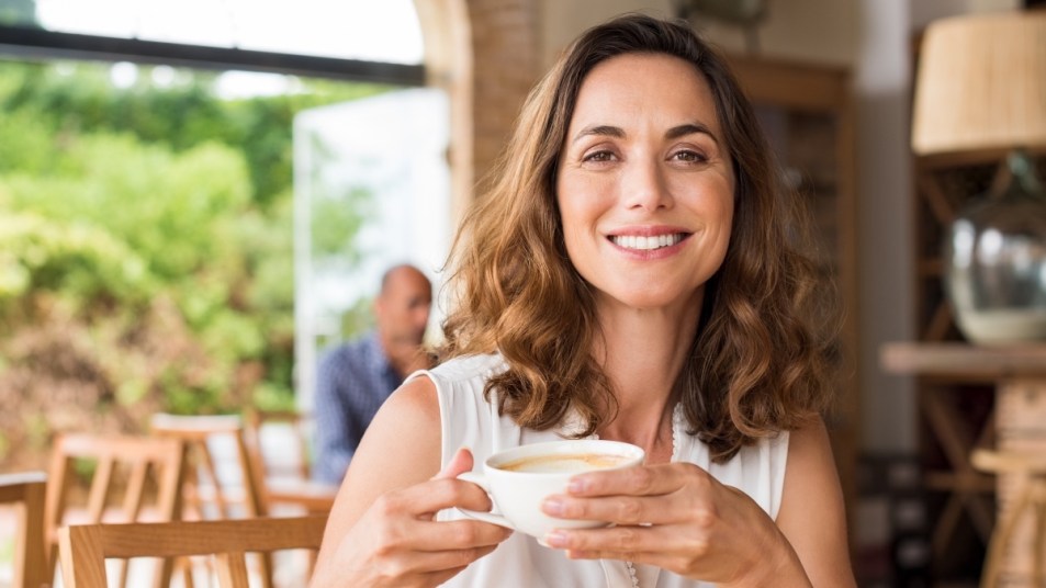 A woman drinking coffee with chlorogenic acid in it in a coffee shop