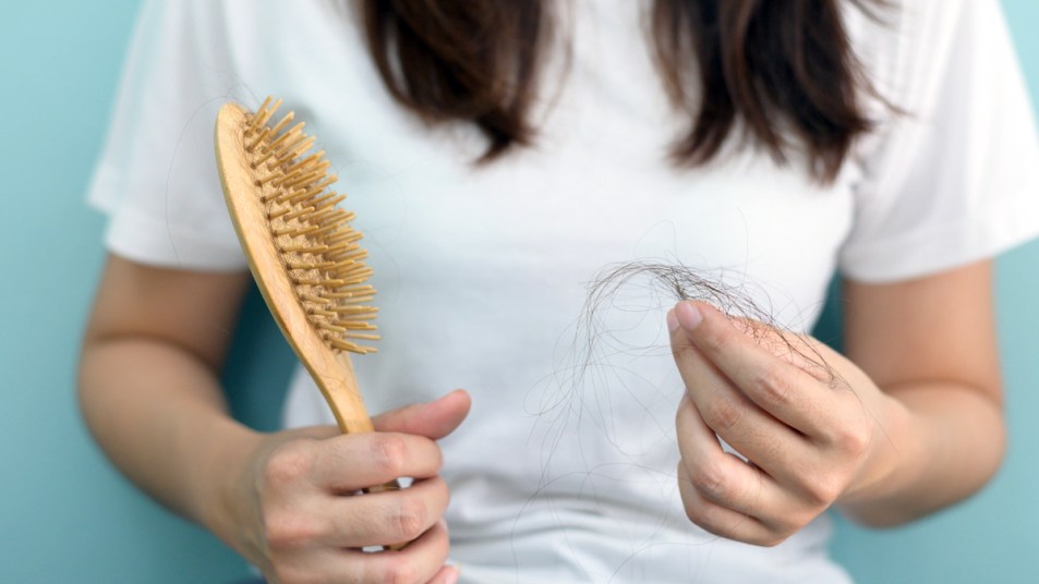 Woman holding hair brush and strands of hair