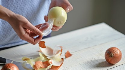 Woman taking the peel off of onion in order to make onion peel tea