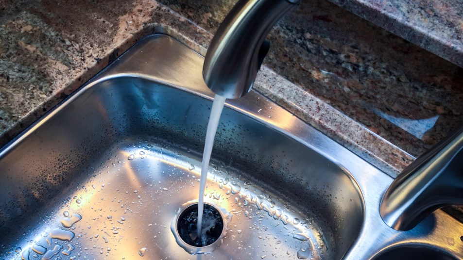 Kitchen sink with water pouring from faucet