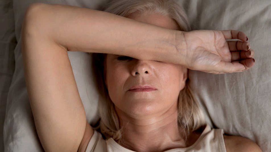 Woman in bed covering her eyes