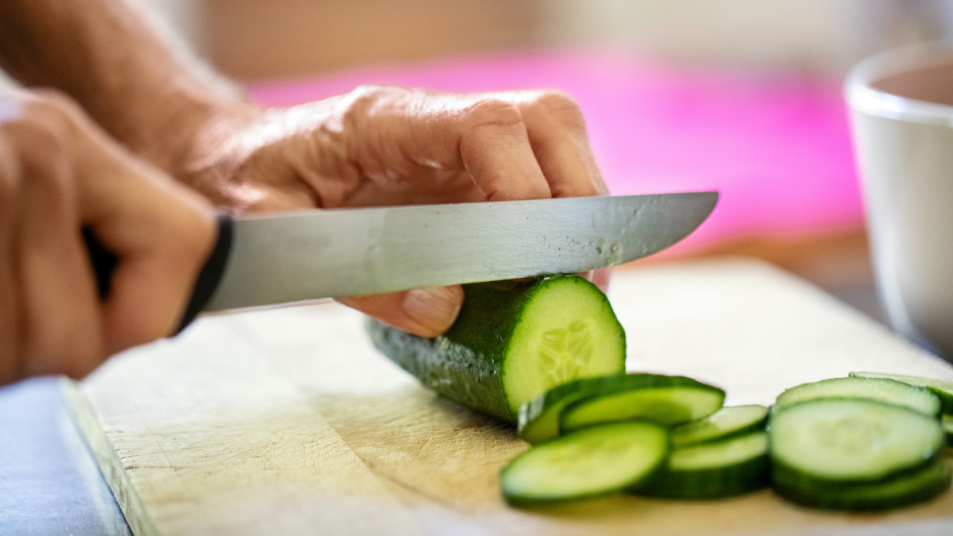 Hands cutting cucumber with knife