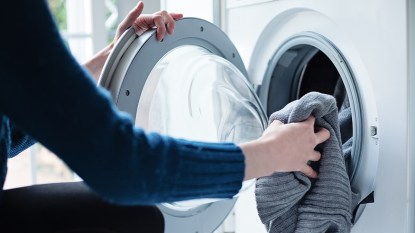 Woman putting in laundry into a washing machine