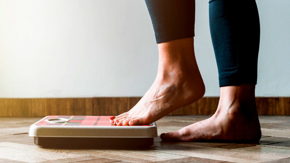 Woman's feet stepping on a scale