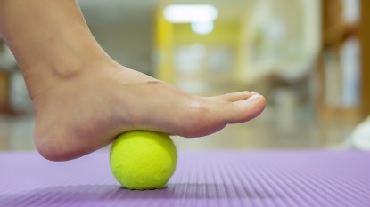 Woman using a tennis ball to ease foot pain