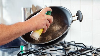 Hand spraying a pan with cooking spray