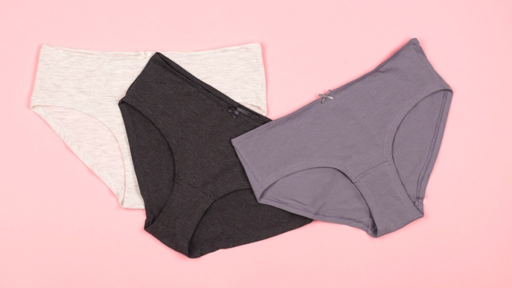 Three pairs of cotton underwear on a pink background