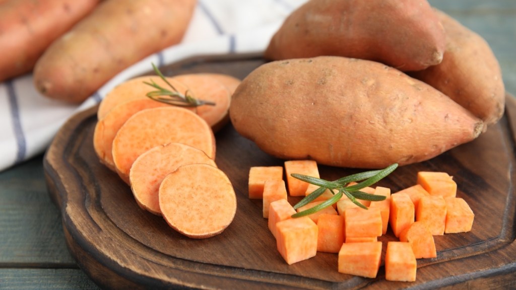 Whole and diced sweet potato on a wood cutting board, a veggie that can help with menopause