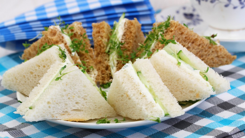 A plate of watercress and cucumber tea sandwiches on a blue checkered napkin