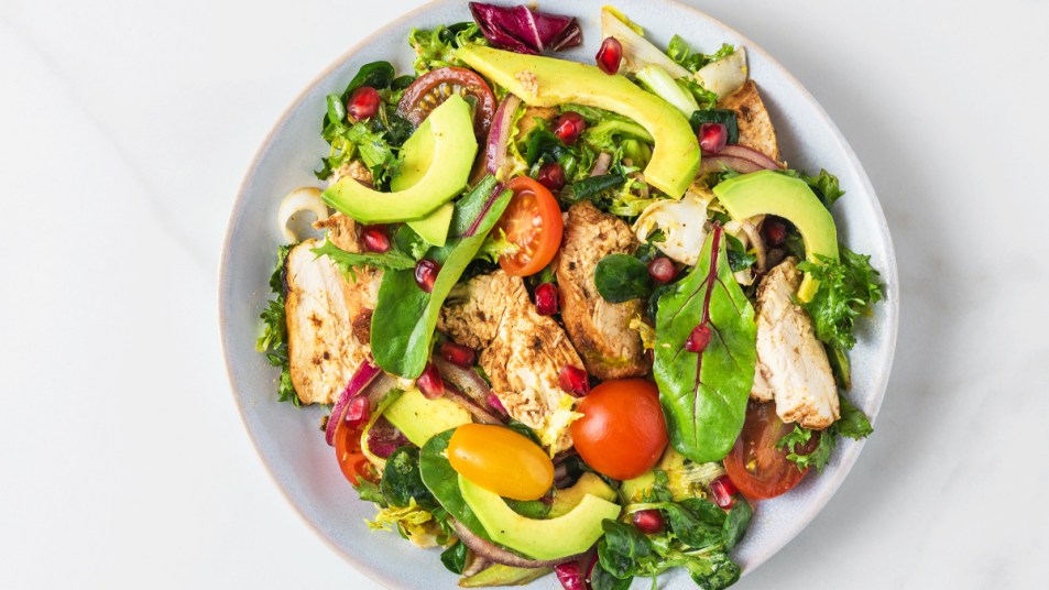 Plate of chicken, leafy greens, avocado, and veggies