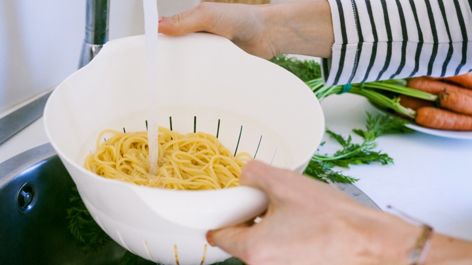 Woman rinsing pasta under tap