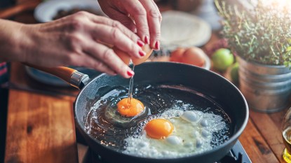 Woman cracking eggs into a pan