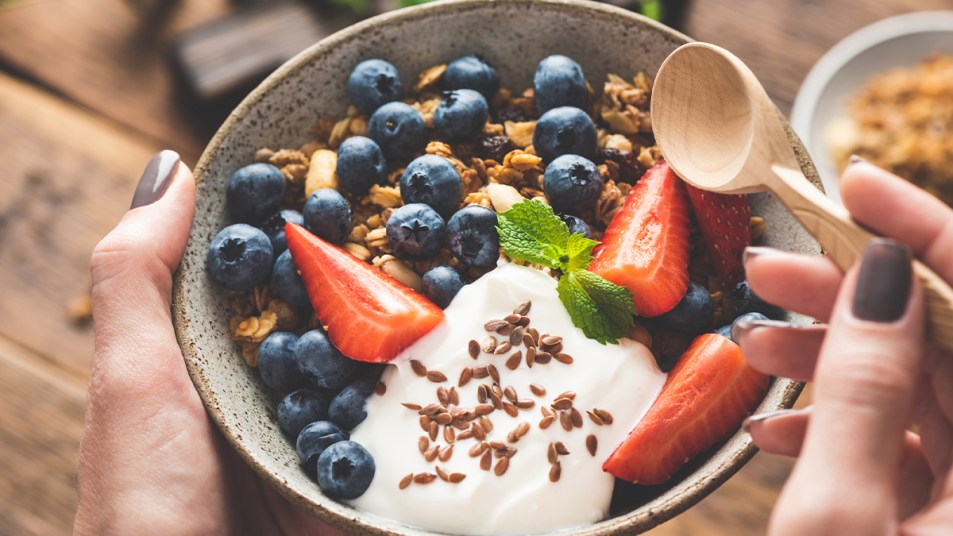 Woman holding a bowl of yogurt with fruit and granola