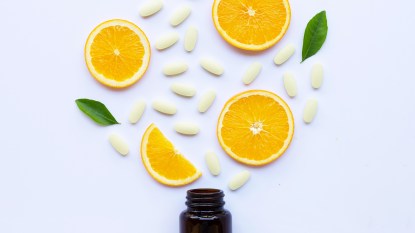 orange slices on a table with vitamin C pills around them