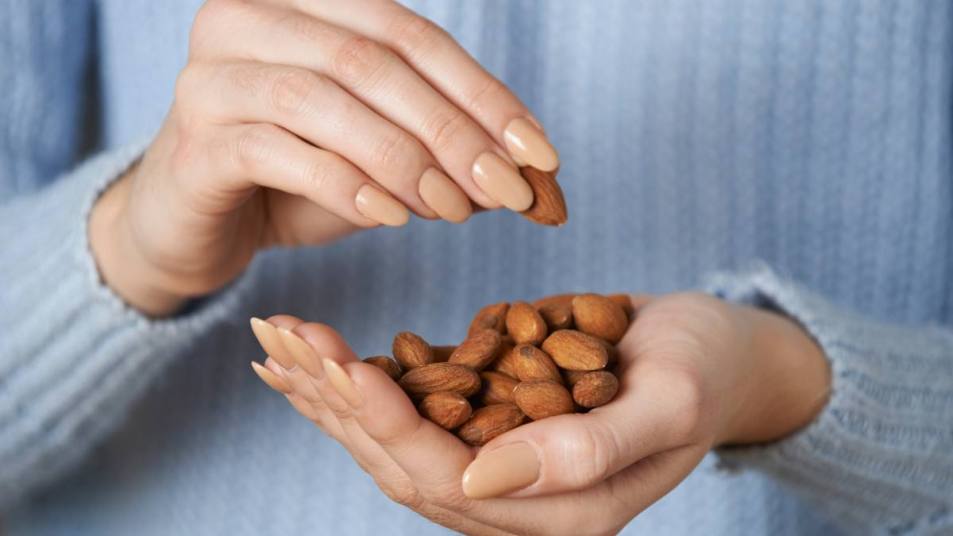 Woman holding a handful of almonds ; Are almonds good for weight loss lead photo