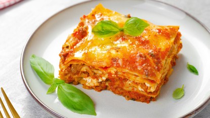 A slice of lasagna served on a plate as part of our guide on how to reheat it