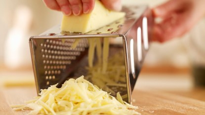 Cheese being grated in cheese grater