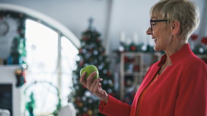 woman eating an apple in front of a christmas tree