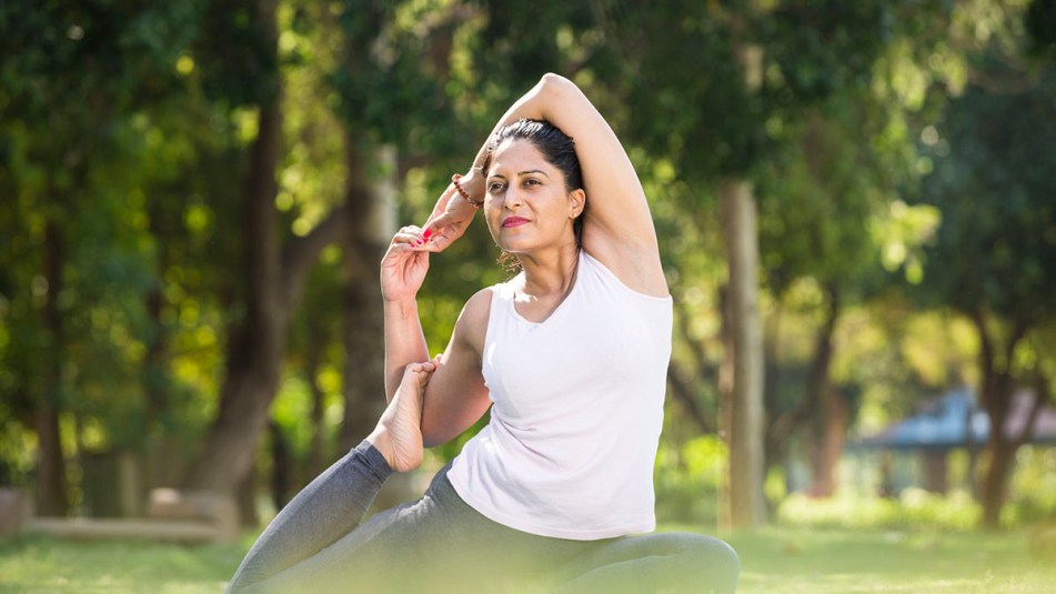 Mature woman builds bone density at the park by engaging in a yoga pose.