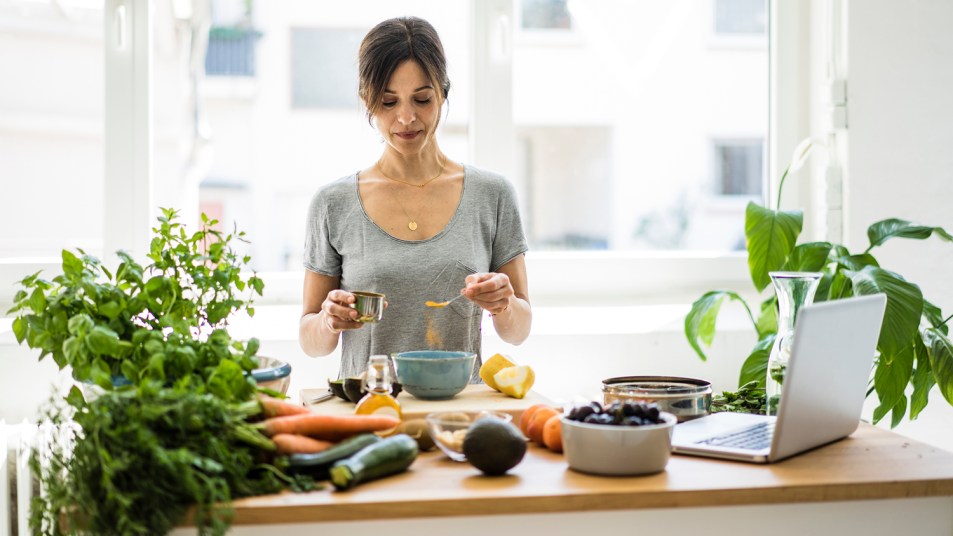 Woman preparing healthy food in her kitchen, using lots of fresh herbs