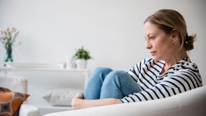 woman feeling stress, sitting in chair holding legs