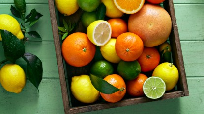 Bright citrus fruits of all kinds overflow out of a wooden box