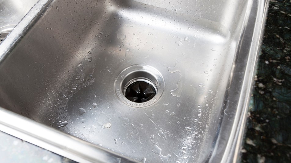 A stainless steel sink with a drain leading to a garbage disposal