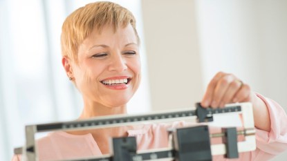 woman on scale losing weight smiling