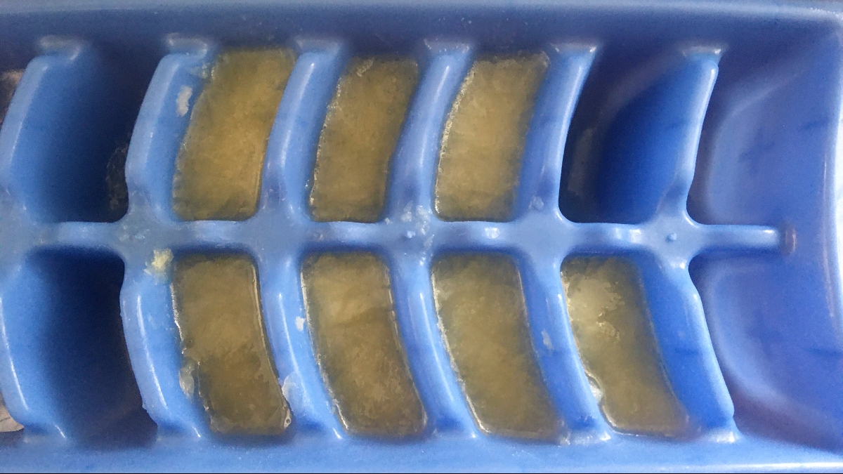 blue ice cube tray filled with lemon juice and pulp