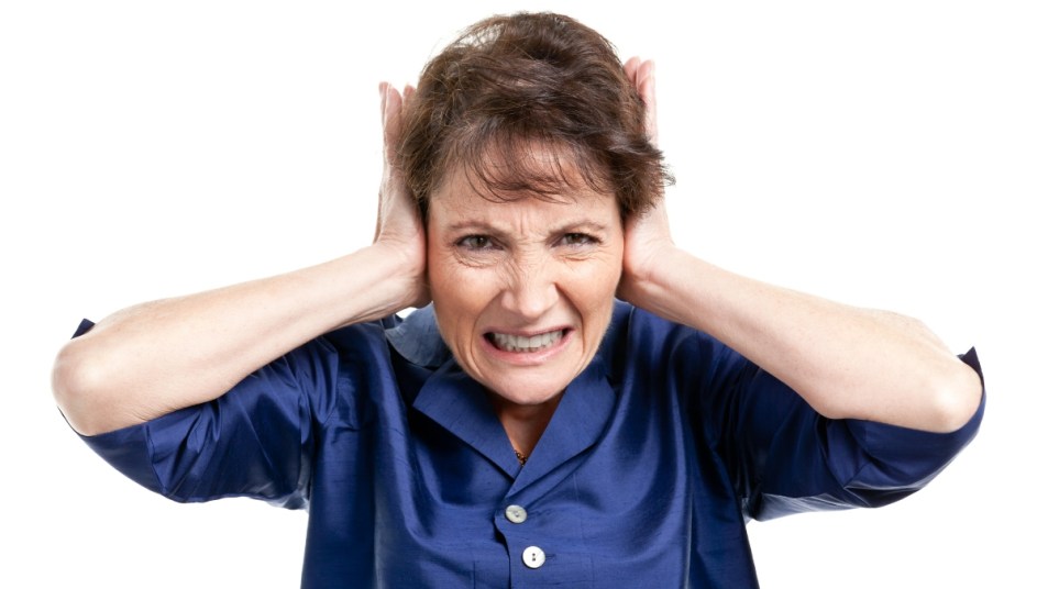 mature woman covering her ears, grimacing