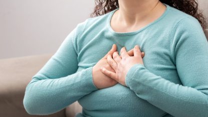 close up on mature woman hand to her chest, heartburn, poor posture concept