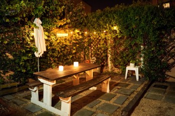 Wooden dining table with candle lights in backyard garden in evening