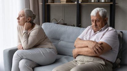 senior married couple facing away from each other, looking unhappy