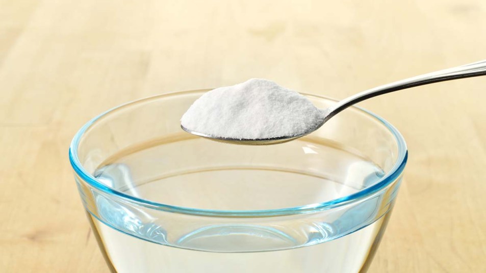 A-spoonful-of-baking-soda-about-to-be-mixed-into-a-glass-of-water