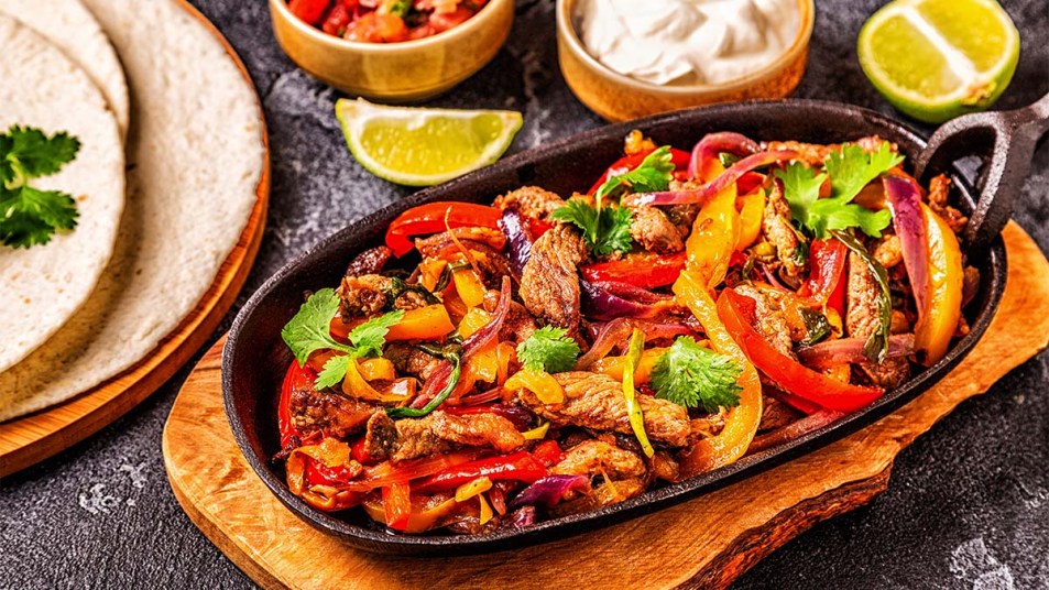 Steak-fajitas-with-colored-pepper-and-onions-served-with-tortillas-salsa-and-sour-cream